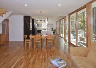 Large living and dining room next to a wall of windows and patio doors